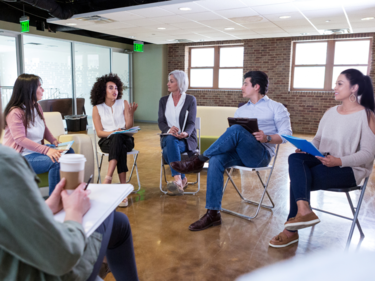Adults sitting in a circle on chairs having a discussion