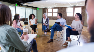 Adults sitting in a circle on chairs having a discussion