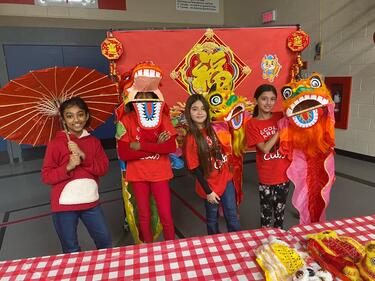 Students dressed in red and wearing or holding items to celebrate Lunar New Year.