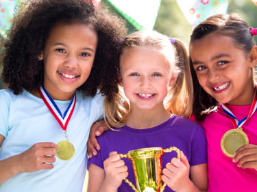 Three girls smiling and holding medals