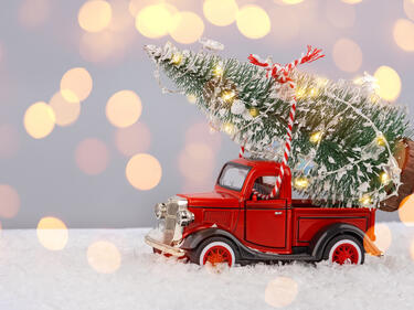 Red toy truck hauling a Christmas tree on faux snow