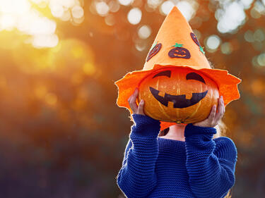 Child holding a jack-o-lantern in front of her face